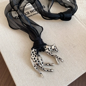 Detail of silver leopard pendant with black spots on a delicate black silk ribbon necklace