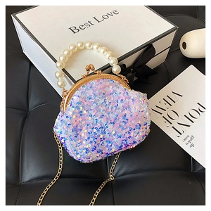 Detail of sequin mini shell bag with pearl handle and golden chain on black background