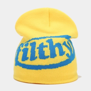 Detailed knit texture of yellow beanie featuring blue filthy jacquard letter design