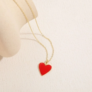 Detail of a 14K gold-plated heart pendant with red enamel on a delicate thin chain