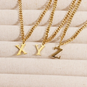 Macro detail of 18K gold plated letter pendants X Y Z on a thin chain necklace