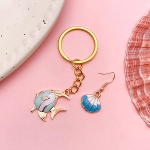 Detail of goldfish keychain and shell earring in gold metal with colorful enamel finish