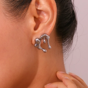 Close-up of liquid metal style silver stud earring with irregular droplet design