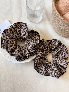 Dettaglio di elastici scrunchie maculati con bordi cuciti neri su un piatto bianco