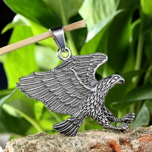 Polished stainless steel eagle pendant with spread wings shown against a natural backdrop