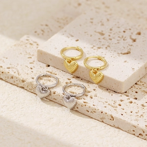 Detail view of gold and silver heart earrings with shell texture on natural stone
