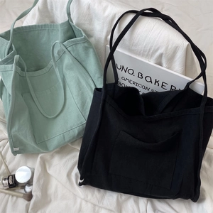 Detail of minimalist canvas tote bags in mint green and black on soft bedding