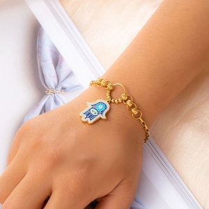 Detail of gold Hamsa Hand bracelet with blue evil eye charm and crystal accents