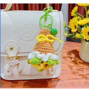Handmade crochet bouquet keychain with bell accessory hanging on a white shoulder bag