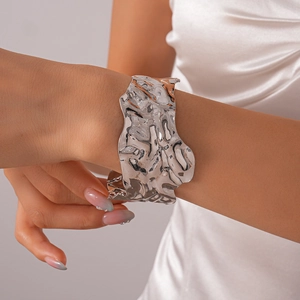 Détail d'un bracelet manchette argenté à texture froissée irrégulière et fini brillant