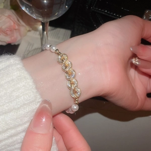 Detailed view of luxury gold bracelet with zircon circles and elegant white pearls on wrist