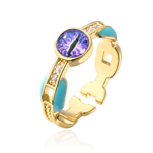 Macro detail of 18K gold-plated eye ring featuring purple stone and blue enamel accents