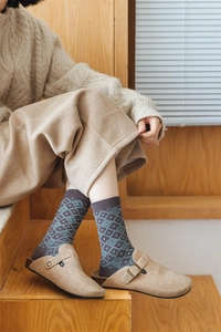 Detail of wool-like argyle socks in retro brown and teal worn with slippers