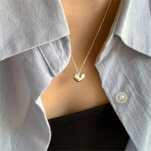 Minimalist silver heart pendant necklace displayed on a model wearing a light blue shirt