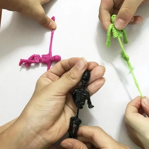 Elastic TPR skeleton toys in black pink and green being stretched on white background