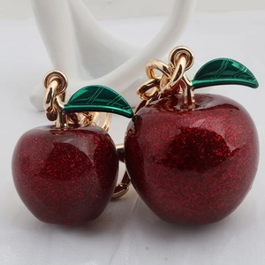 Macro detail of two red apple keychains with glitter finish and golden rings
