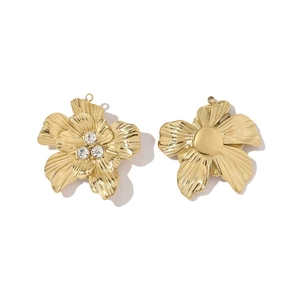 Detailed view of two golden titanium steel flower charms with rhinestones and smooth metal centers