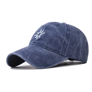 Detailed close-up of white sun embroidery on washed navy blue cotton baseball cap