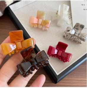 Close-up of small acetate bow hair clips in amber, tortoiseshell, and marble patterns