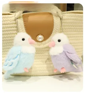Blue and purple plush bird charms hanging on a beige bag with silver ball chains