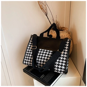 Macro view of vintage houndstooth tote bag with premium black leather trim and metal clasp
