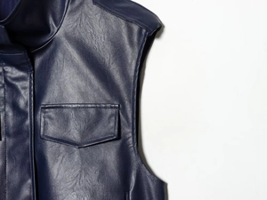 Detail of faux leather vest showing litchi texture and sewing on the navy blue collar