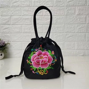 Detailed close-up of pink peony embroidery on black canvas drawstring bucket bag