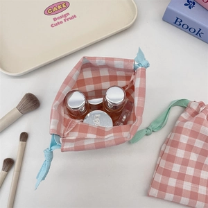 Detail of pink plaid drawstring organizer bag with cosmetics for travel storage