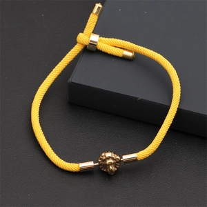 Detailed close-up of yellow braided rope bracelet with bronze lion head charm and slider