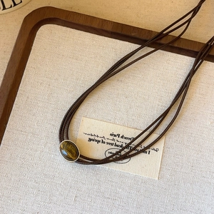 Detailed close-up of tiger eye stone pendant necklace on rustic wooden and linen background