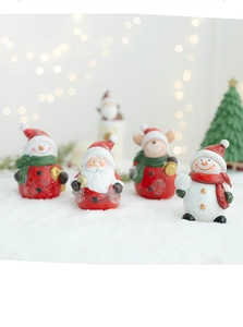 Close-up of mini resin Santa, snowman, and reindeer figurines on decorative snow