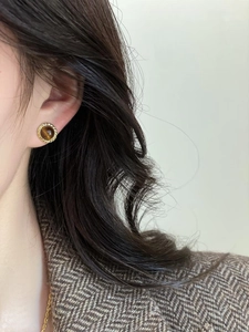 Gros plan d'un mannequin portant un collier doré rond avec pendentif œil de tigre brun