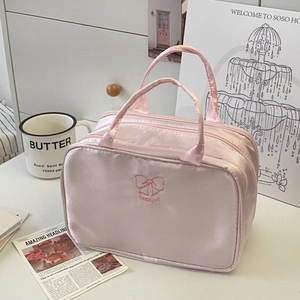 Dettaglio della borsa per cosmetici in raso rosa con fiocco e ricamo Lucky