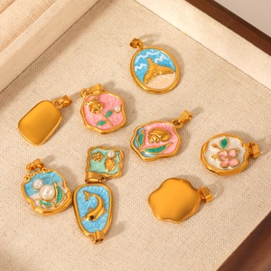 Golden ocean charms collection with colorful enamel patterns in a wooden display tray
