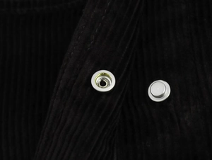Vue macro détaillée de la texture du velours côtelé noir et des boutons-pression en métal