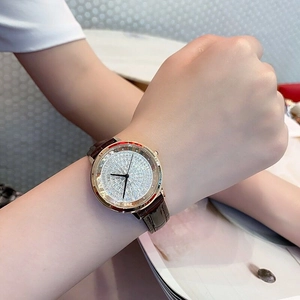 Close-up of a luxury rose gold crystal watch with brown leather strap on woman's wrist