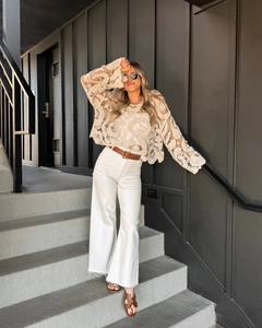 Detail of crochet hollow-out beach cover-up paired with white wide-leg pants and belt