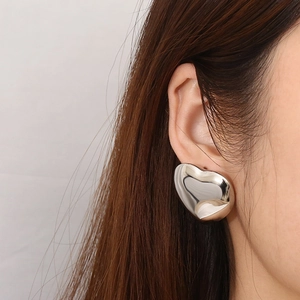 Close-up of minimalist silver heart-shaped earring on model showing modern style