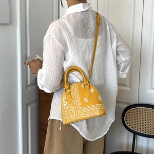 Detail of yellow shell bag with white paisley print and gold-tone hardware for women