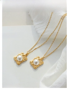 Close-up of elegant gold necklaces with rectangular pearl pendants on a white book