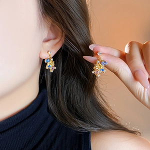 Elegant gold earrings with colorful crystals and rhinestones on woman's ear