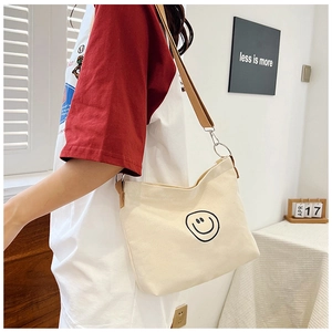 Detail of canvas bag showing the black smile face print and brown adjustable strap