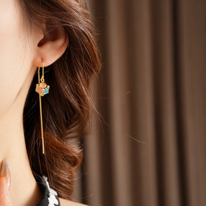 Detail of gold-plated long earrings with cat eye stones and cubic geometric pendants