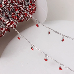 Macro detail of silver plated chain with red round gemstone pendants for DIY jewelry