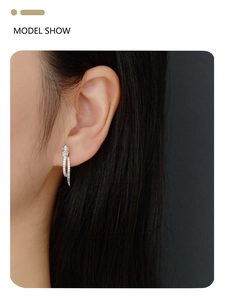 Close-up of a silver snake-shaped earring with clear stones worn by a model