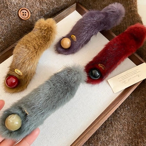 Detail of plush faux fur hair clips with round beads and golden Lucky metal tag