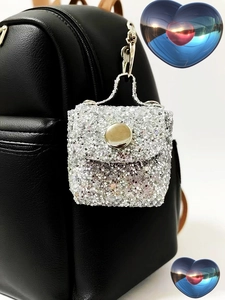 Macro shot of a silver glitter mini bag keychain attached to a black backpack