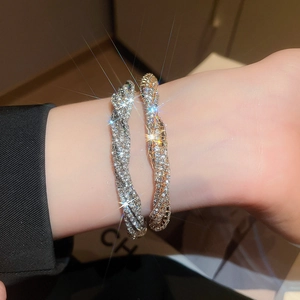 Macro shot of silver and gold layered wrap bracelets with shimmering pavé crystal detail