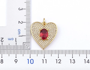 Detail of gold heart necklace with a red oval gemstone and cubic zirconia accents