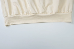 Detailed close-up of cream knit ribbed hem showing premium stitching and fabric texture